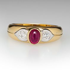 This lovely ring is centered with one (1) oval cabochon cut natural ruby set into a bezel. The shoulders are each accented with one (1), flush set, round brilliant cut diamond. The ring measures 6.7mm at the top, rises 6.8mm above the finger, tapering to 3.1mm wide and 0.8mm thick at the base of the shank. This ring is currently a size 8.5. Luxury Ruby And Diamond Oval Cabochon Ring, Luxury Ruby Ring With Oval Cabochon Diamond, Oval Cabochon Ruby And Diamond Ring, Oval Cabochon Ruby Ring With Diamonds, Classic Diamond Ring With Cabochon Cut, Classic Diamond Cabochon Ring, Formal Ruby Ring With Diamond And Oval Cabochon Shape, Elegant Ruby Ring With Oval Diamond, Formal Oval Cabochon Ruby Ring With Diamond