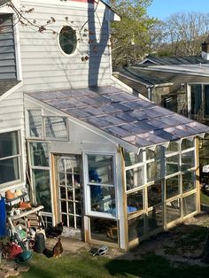 a small house with a solar panel on the roof and windows in front of it