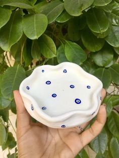 a hand holding a white bowl with blue dots on it