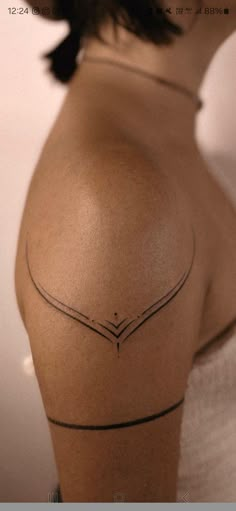 the back of a woman's shoulder with an arrow tattoo on her left side