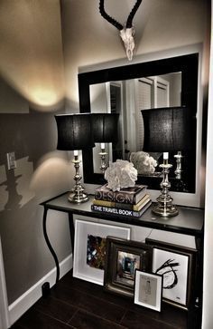 a black and white console table with pictures on it, lamps and a deer's head mounted to the wall