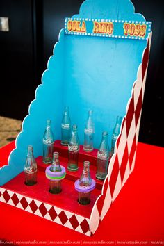 there are many empty bottles in the box on the red tablecloth and blue wall behind it