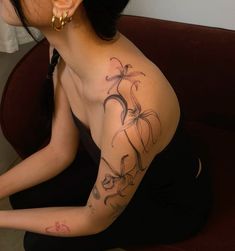 a woman sitting on the floor with her arm tattooed to look like an orchid