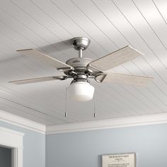 a ceiling fan in a room with light blue walls and white paneling on the ceiling