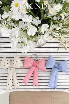 three small bows are on top of a table with flowers in front of it and the words mom's day written above them