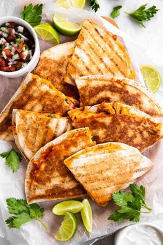 quesadillas on a plate with salsa and limes