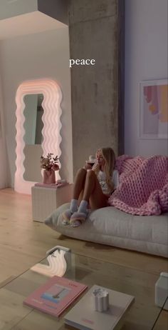 a woman sitting on top of a white couch next to a table with a cup of coffee