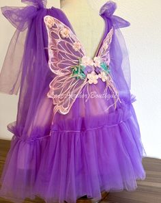 Flutter into summer with this vibrant purple girls dress! Adorned with flowers, butterflies, and playful wings on the back, this tulle dress is sure to make your little one feel like a fairy. The cute tied bow shoulder adds the perfect finishing touch to this dreamy dress. Size 3T Zip closure on back Purple Fairy Dress With Ruffles For Birthday, Sleeveless Purple Fairy Dress With Ruffles, Fairy Butterfly Wings Dress, Pageant Ooc, Purple Fairy Wings, Whimsical Purple Tutu Dress For Dress-up, Strawberry Outfit, Purple Fairy Dress Toddler, Flower Girl Outfits