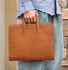 a person holding a brown briefcase in their hand