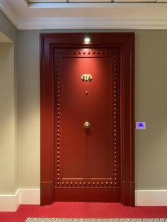 an open red door in the middle of a room with carpeting on the floor