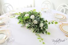 the table is set with white flowers and greenery