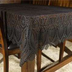 a table with a black crochet doily draped over it on top of a wooden chair