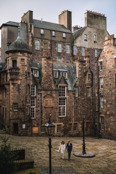 two people walking in front of an old building