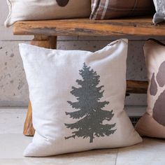 three pillows with different designs on them sitting next to each other in front of a bench