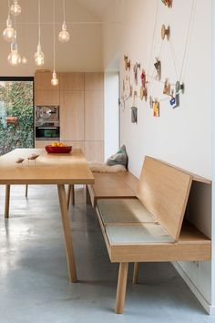 a wooden bench sitting in the middle of a living room next to a dining table