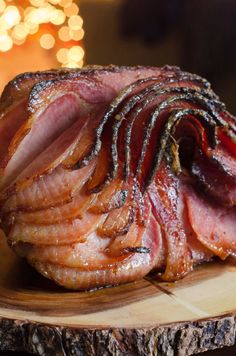 sliced ham sitting on top of a wooden cutting board next to a lit christmas tree