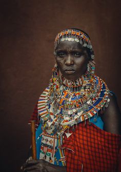 an african woman in traditional dress and headdress poses for the camera with her hand on her hip