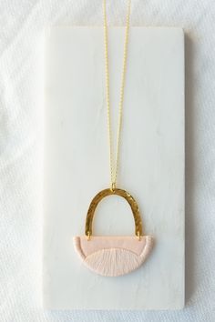 "This series of pendants were inspired by the landscapes we explored with our little ones in the summer. Rolling hills and peaks all to be found in Yorkshire. This small pendant is made from Blush cotton and is fully interfaced to provide support. I have stitched the edges and curved pattern using a matching Blush thread. This is suspended under a hammered brass arc and hangs from an 18\" chain of gold vermeil (sterling silver plated with 18ct gold). I have enamelled the brass arc to prevent tar Pink Handmade Minimalist Necklaces, Handmade Minimalist Pink Necklaces, Pink Handmade Minimalist Necklace, Minimalist Handmade Pink Necklace, Handmade Minimalist Pink Necklace, Handmade Pink Jewelry For Everyday, Handmade Pink Everyday Necklaces, Handmade Pink Necklaces For Everyday Wear, Handmade Pink Necklace For Everyday