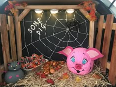 a pink pig head sitting on top of hay in front of a blackboard with writing