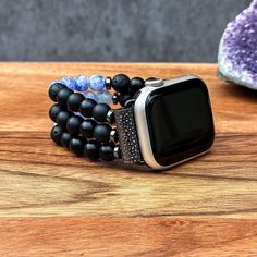 Transform your Apple Watch into a striking statement piece with our handcrafted Black Matte Onyx, Black Volcanic Lava, and Blue Cracked Agate gemstone watch band. Designed to blend versatility with elegance, this band fits all Apple iWatch Series 1/2/3/4/5/6/7/8/9/SE and Ultra, accommodating various sizes including 38mm/40mm/41mm and 42mm/44mm/45mm/49mm. Each band is meticulously crafted with high-quality Black Matte Onyx, Black Volcanic Lava, and Blue Cracked Agate beads, providing a sophisticated touch while ensuring a comfortable fit. Personalize the band length for a perfect fit around your wrist, enhancing both style and comfort. Suitable for both men and women, this unique watch band turns your Apple Watch into a stunning piece of jewelry, making it an exceptional gift for any occasi Adjustable Black Beaded Apple Watch Band, Black Bracelet Strap Apple Watch Band As Gift, Modern Apple Watch Band As Gift, Elegant Black Apple Watch Band For Gift, Elegant Black Apple Watch Band Gift, Handmade Black Watch As A Gift, Handmade Black Watch For Gift, Handmade Black Watches As Gifts, Handmade Black Watches As A Gift