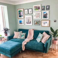 a living room with blue couches and pictures on the wall above them, along with potted plants