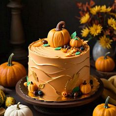 a cake decorated with pumpkins and leaves on a table next to other fall decorations