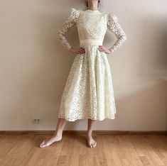 a woman standing in front of a wall with her hands on her hips wearing a white dress