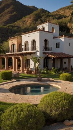 a large white house with a pool in the front yard and mountains in the background