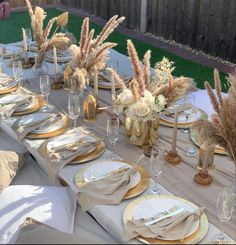 the table is set with gold and white plates, napkins, silverware, and flowers