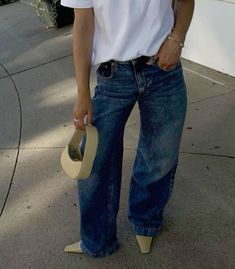 a woman standing on the sidewalk with her hat in her hand