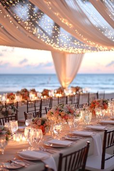 the tables are set up with candles and place settings for an elegant wedding reception on the beach