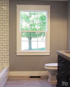 a white toilet sitting under a window in a bathroom next to a sink and bathtub