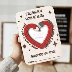 a person holding up a card with a heart on it and the words teaching is a work of heart