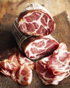 several pieces of meat sitting on top of a wooden cutting board