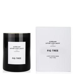 a black candle next to a white box on a white surface with the words fig tree printed on it