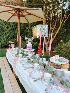 a table topped with lots of cake and cupcakes next to a wooden bench