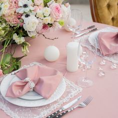 a table set with pink napkins, white plates and silverware