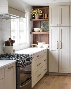 a kitchen with white cabinets and an oven in the center, surrounded by wooden flooring