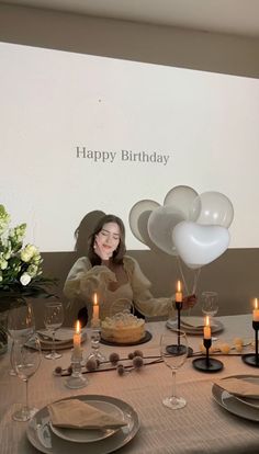 a woman sitting at a table in front of a birthday cake with candles on it