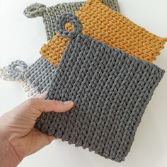 a hand is holding two knitted items