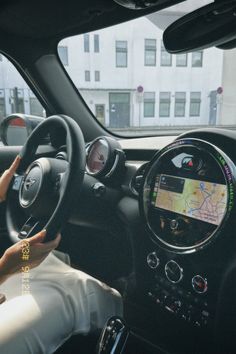 a woman sitting in the driver's seat of a car with her hand on the steering wheel