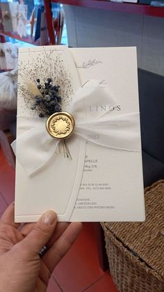 a person holding up a wedding card with a wax stamp on it