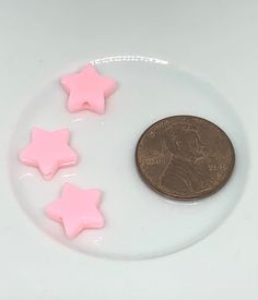 three little pink stars on a plate next to a penny