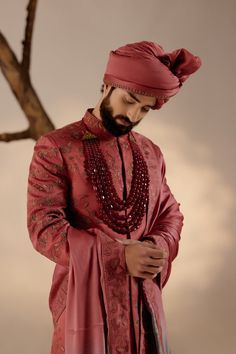 a man wearing a red turban standing next to a tree