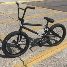 a black bike sitting on top of a parking lot next to a yellow stripe line