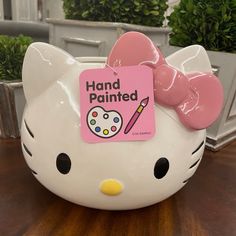 a hello kitty piggy bank sitting on top of a wooden table