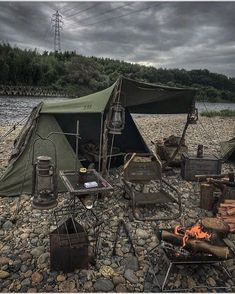 a tent is set up on the ground next to a fire