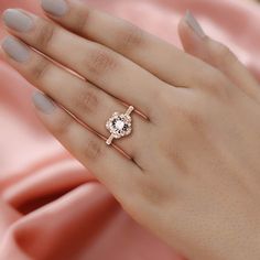 a woman's hand wearing a ring with an oval shaped diamond in the center