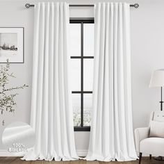 a white curtain hanging in front of a window with a chair and pictures on the wall