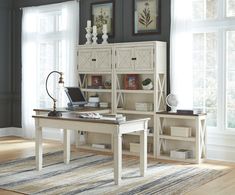 a white desk sitting in front of a window next to a book shelf and chair